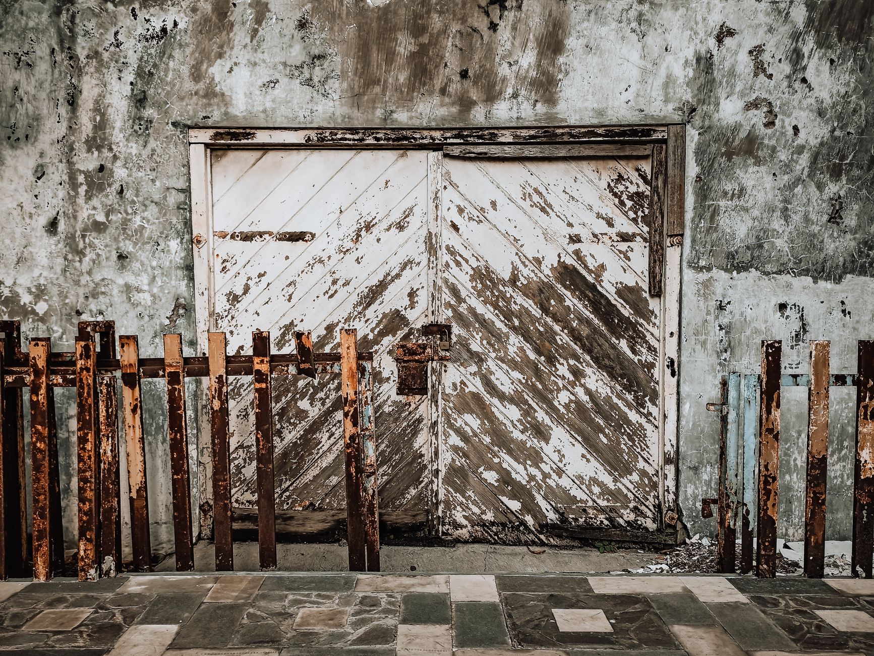 A vintage wooden door with chipping paint alongside a rusty metal fence creates an artistic scene